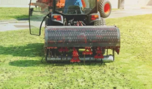 Tractor performing lawn aeration on a green yard to improve soil health and promote thicker grass growth in Austin.