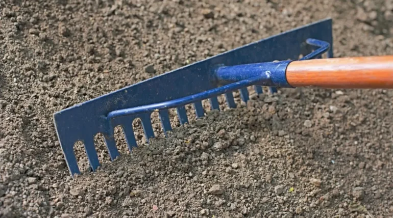 Rake performing lawn leveling on soil to create an even surface and improve irrigation efficiency in Austin.
