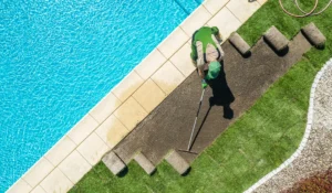 Professional landscaper leveling soil to Level Your Lawn in Austin, preparing smooth ground for healthier turf near a backyard pool.